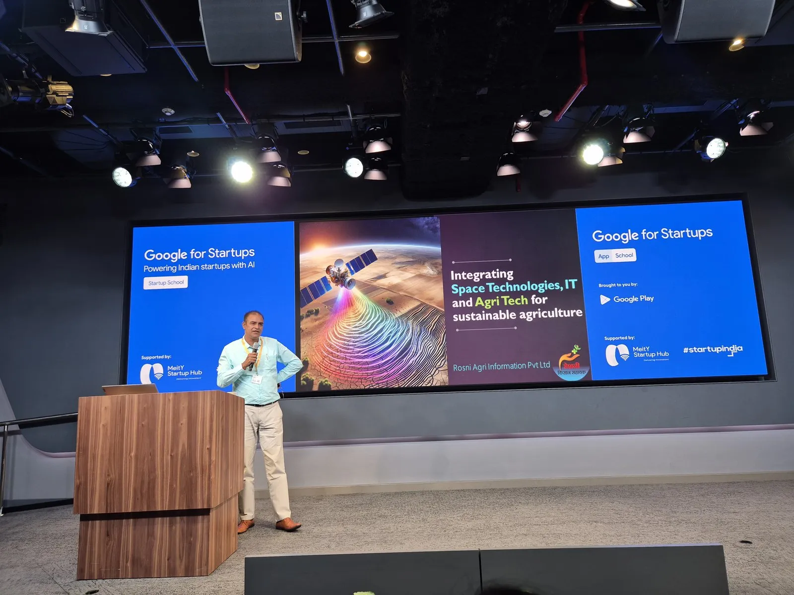 Rajeev Tomer presenting on stage at a Google for Startups Startup School event, with a Rosni title slide behind him reading “Integrating Space Technologies, IT and Agri Tech for sustainable agriculture — Rosni Agri Information Pvt Ltd”.